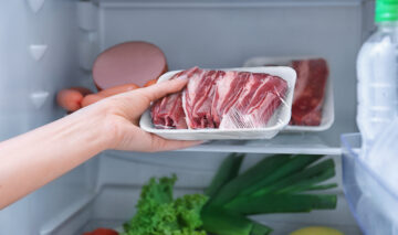O femeie care pune carnea înfoliată în frigider