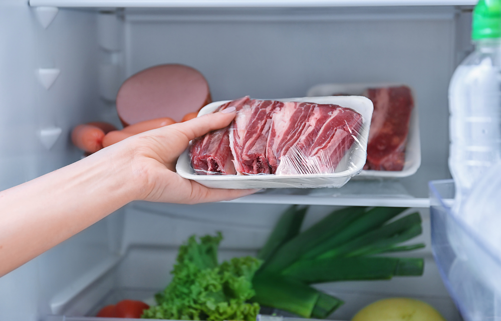 O femeie care pune carnea înfoliată în frigider
