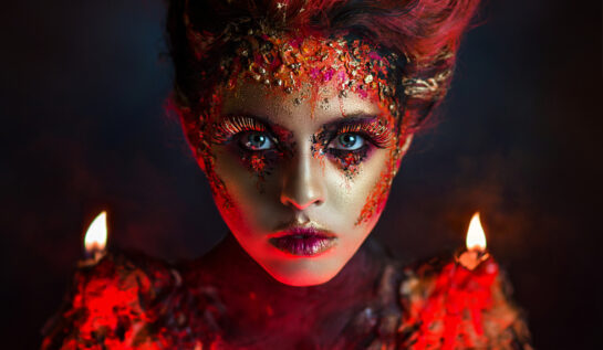 O femeie frumoasă, cu ochi albaștri, machiată în nuanțe de roșu și auriu, pentru a ilustra zodii cu un temperament vulcanic