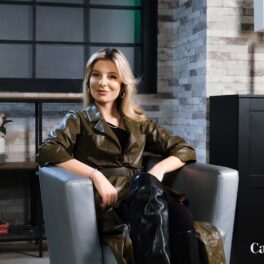 Ana Baniciu într-o jachetă verde în timp ce stă pe un fotoliu gri la interviul CaTine.ro