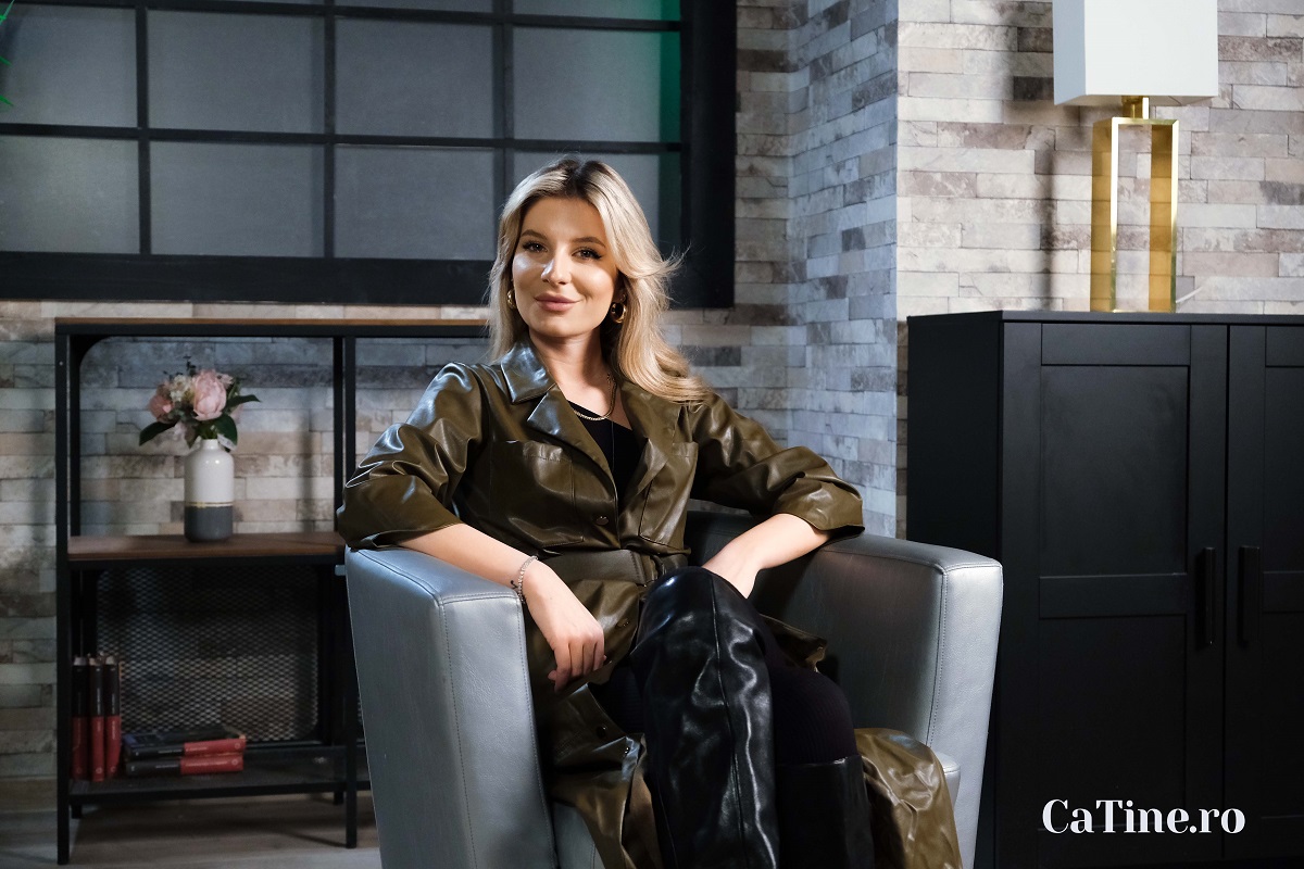 Ana Baniciu într-o jachetă verde în timp ce stă pe un fotoliu gri la interviul CaTine.ro