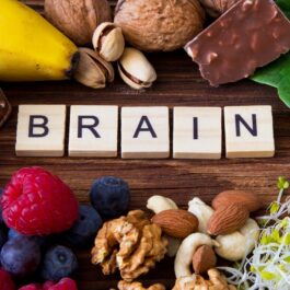 Un blat de lem pe care se află nuci, semințe, fructe de pădure, ciocolată neagră și frunze de spanac pentru a ilustra cele mai bune alimente pentru stimularea funcțiilor creierului