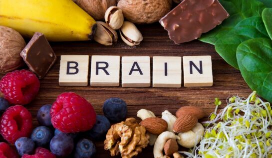 Un blat de lem pe care se află nuci, semințe, fructe de pădure, ciocolată neagră și frunze de spanac pentru a ilustra cele mai bune alimente pentru stimularea funcțiilor creierului