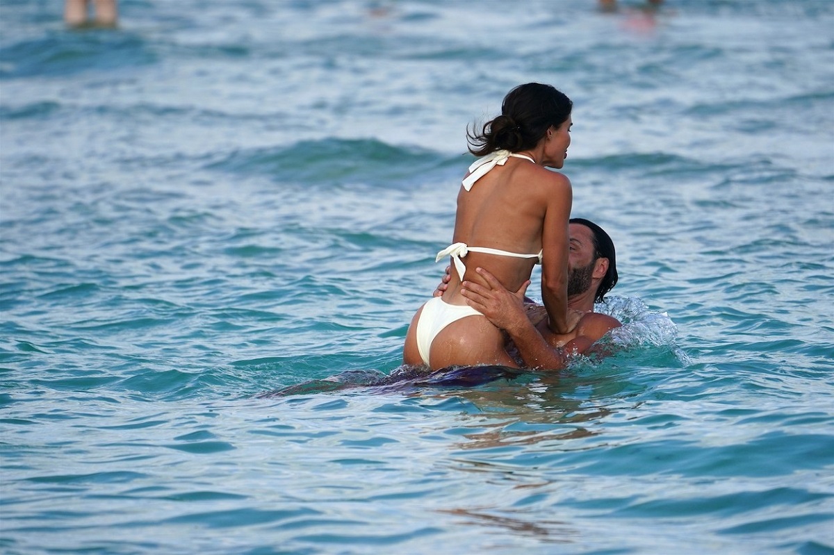 David Guetta în timp ce își ține în brațe iubita, Jessica Ledon, și o ridică în valurile oceanului