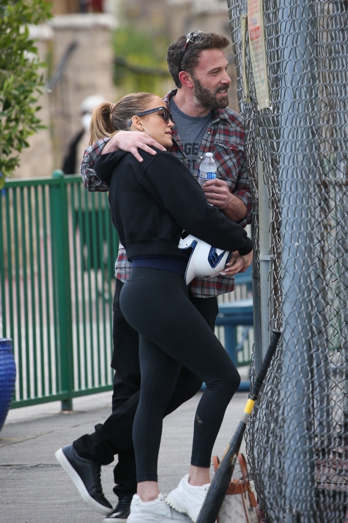 Jennifer Lopez într-un trening negru în timp ce stă în brațele iubitului său, Ben Affleck și o primvește pe fiica sa, Emme, jucând baseball