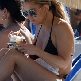 Kate Hudson într-un costum de baie negru în timp ce bea dintr-o băutură