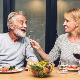 Un cuplu cu un domn în vârstă și o doamnă care iau masa împreună pentru a ilustra obiceiul care îți afectează silueta atunci când înaintezi în vârstă