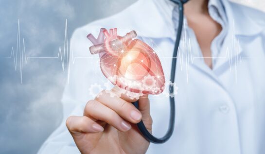 Un medic în halat alba care ține un stetoscop în mână cu un simbol al inimii umane