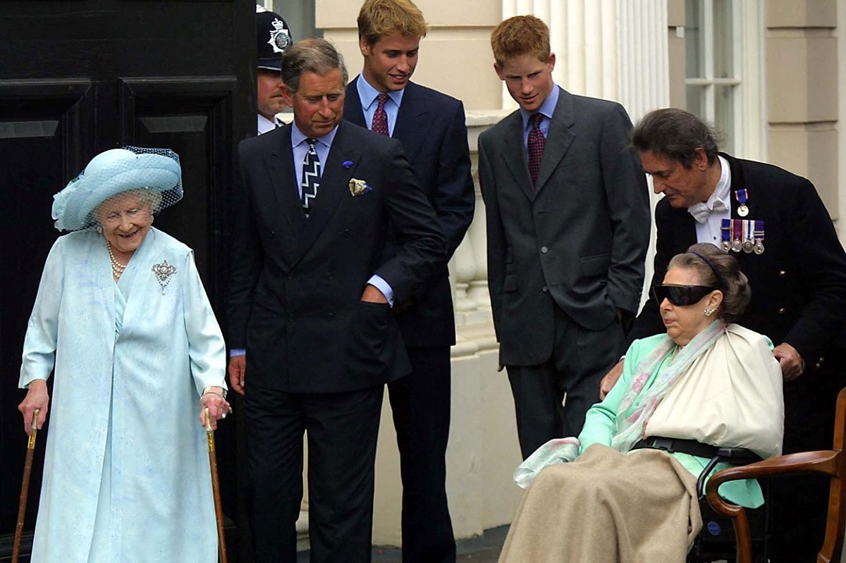 Regina Mamă alături de Prințul Charles, Prințul William și Harry care o privesc pe Prințesa Margaret care se află într-un scaun cu rotile în anul 2001 la celebrarea avinersării a 101 ani a Reginei Mamă
