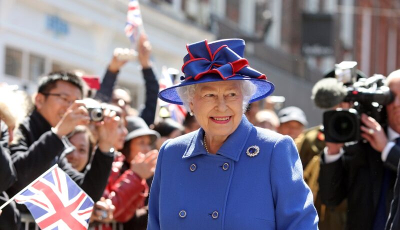 Regina Elisabeta într-un costum albastru în timp ce se află într-o vizită oficială la Universitatea Cambridge în anul 2017