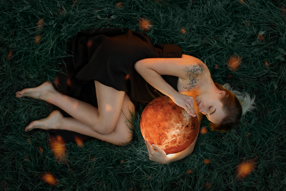 Femeie frumoasă stă întinsă pe jos și ține un glob portocaliu în mână