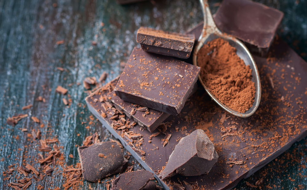 Ciocolată neagră și pudră de cacao pe un blat închis la culoare