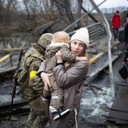 O femeie care ține un copil în brațe în timp ce este evacuată din Ucraina