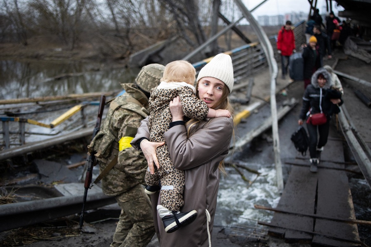 O femeie care ține un copil în brațe în timp ce este evacuată din Ucraina