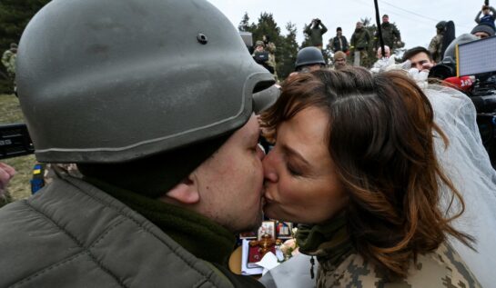 Mire și mireasă care se sărută după ce s-au căsătorit pe frontul de luptă