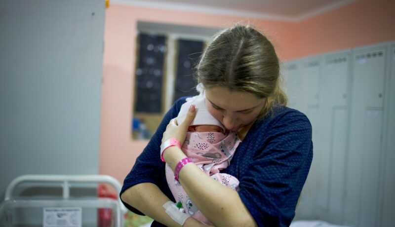 O femeie ține un nou-născut în brațe, într-un spital din Ucraina