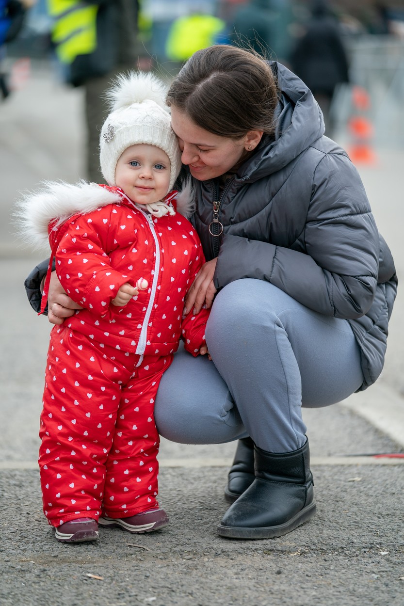 O fetiță într-un costum roșu, care a plecat din Ucraina cu mama sa