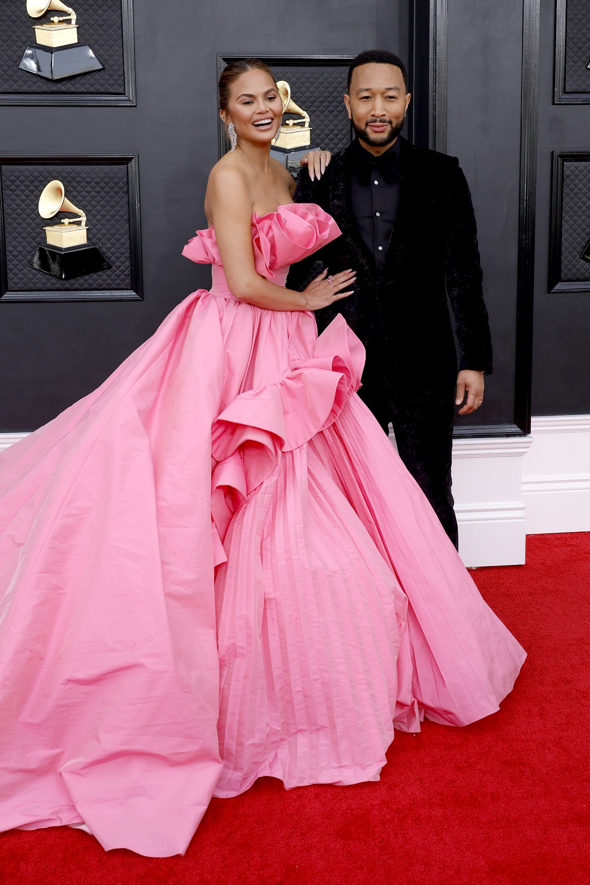 Chrissy Teigen într-o rochie roz alături de John Legend pe covorul roșu la premiile grammy 2022