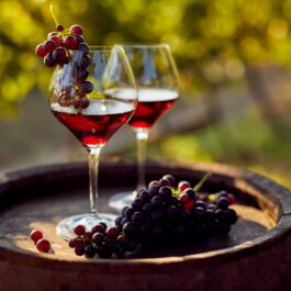 Două pahare de vin care stau pe un butoi pentru a ilustra că paharul de vin poate să te ajute să pierzi în greutate dacă este consumat în fiecare seară
