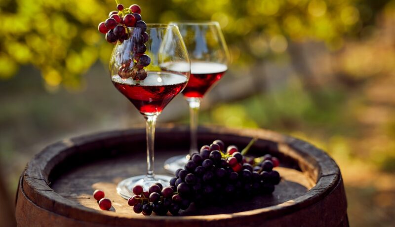 Două pahare de vin care stau pe un butoi pentru a ilustra că paharul de vin poate să te ajute să pierzi în greutate dacă este consumat în fiecare seară