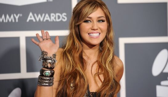 Miley Cyrus cu părul lung și castaniu în timp ce pozează pe covorul roșu la Premiile Grammy din anul 2011