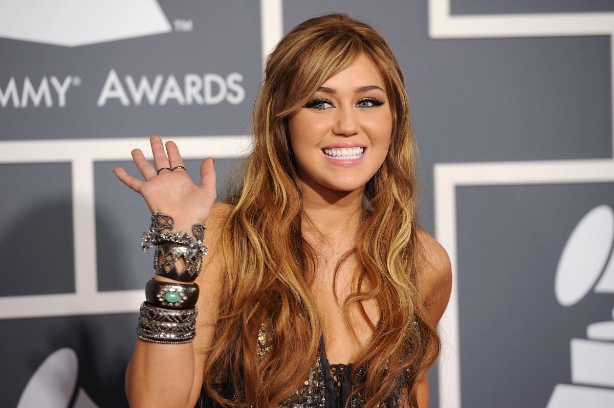 Miley Cyrus cu părul lung și castaniu în timp ce pozează pe covorul roșu la Premiile Grammy din anul 2011