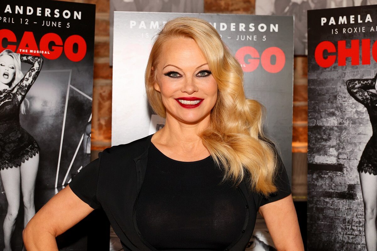 Pamela Anderson în timp ce se pozează în fața unui panou publicitar cu musicalul Chicago