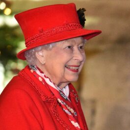 Regina Elisabeta îmbrăcată într-un costum roșu din două piese la un eveniment public