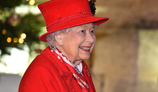 Regina Elisabeta îmbrăcată într-un costum roșu din două piese la un eveniment public