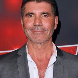 Simon Cowell îmbrăcat la un costum gri și o cămașă albă în timp ce face parte din juriul Americanii au Talent în anul 2021