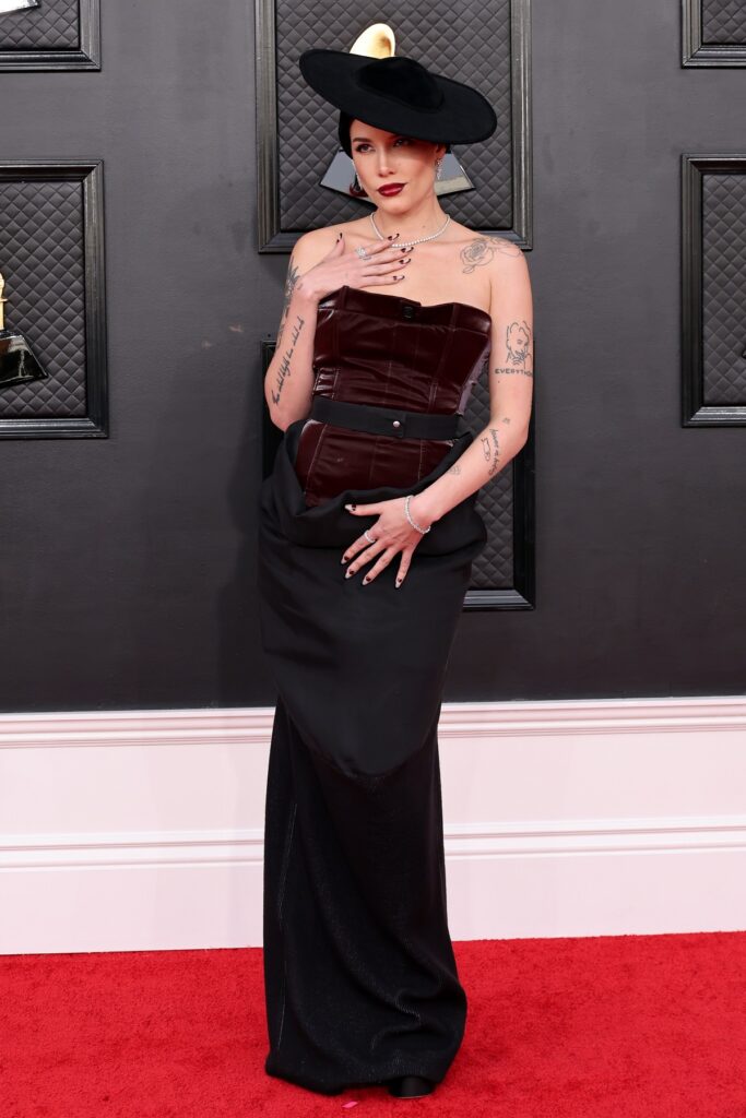 Cântăreața Halsey într-o rochie neagră cu o pălărie în timp ce pozează pe covorul roșu de la Premiile Grammy 2022