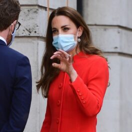 Kate Middleton într-un palton roșu în timp ce are un deget bandajat