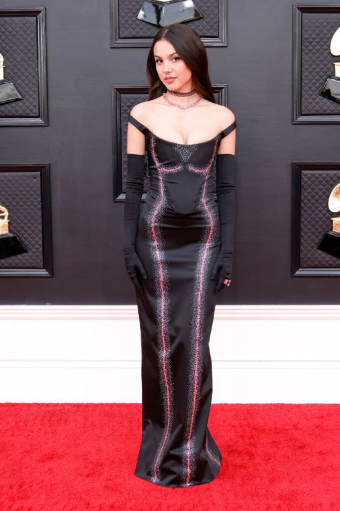 Olivia Rodrigo într-o rochie neagră în timp ce pozează pe covorul roșu de la Premiile Grammy 2022