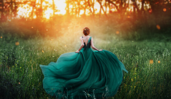 Fată frumoasă aleargă în pădure cu o rochie verde lungă