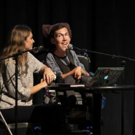 Shane Burcaw, pe o scenă, la o conferință, alături de soția sa