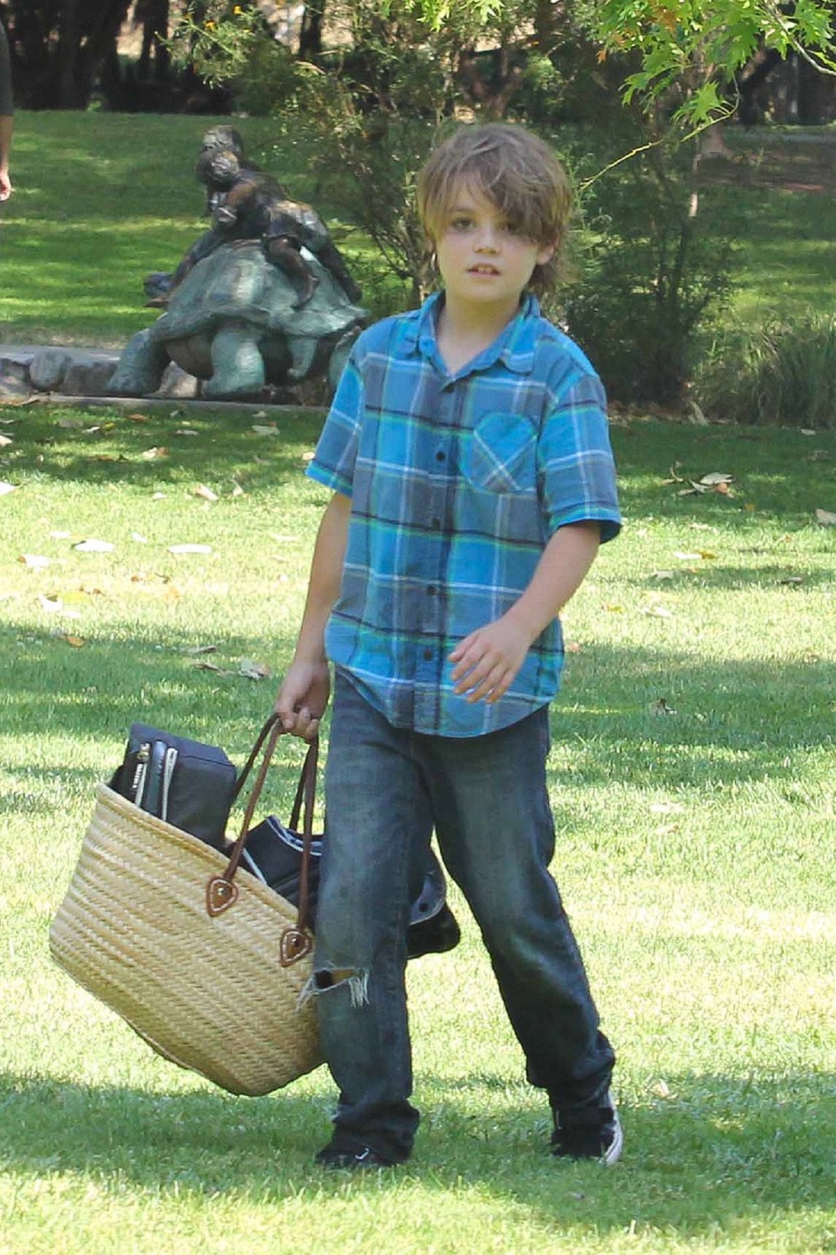 John Jack Depp, în copilărie, într-o cămașă albastră în carouri în timp ce duce un coș în mână