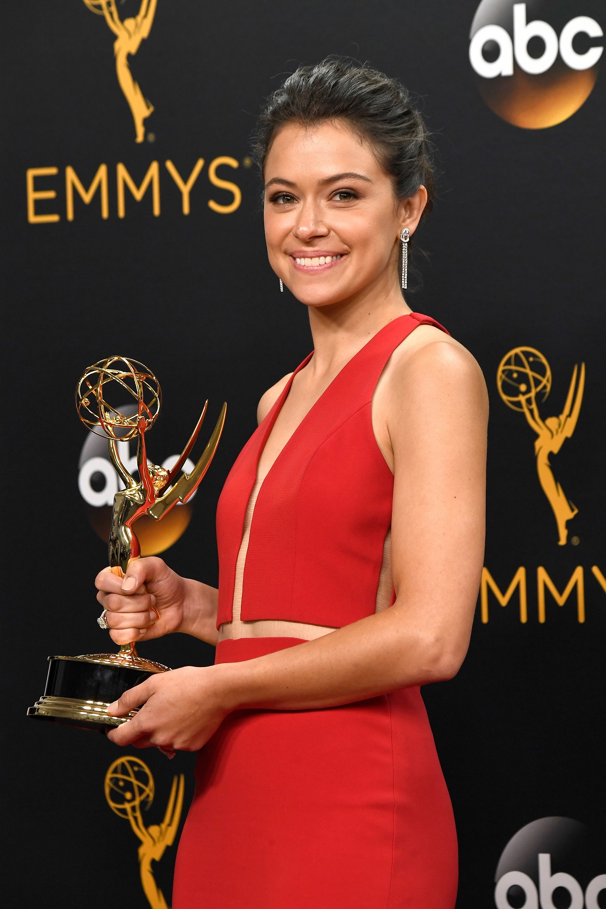 Tatiana Maslany într-o rochie roșie cu Premiul Emmy în mână în anu 2016