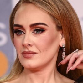 Adele în timp ce își aranjează părul pe covorul roșu la BRIT Awards 2022