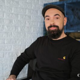 Claudiu Teohari, pe un scaun, în haine negre, la interviul CaTine.ro
