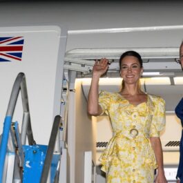 Kate Middleton într-o rochie galbenă alături de Prințul William îmbrăcat la costum în timp ce îi salută pe oamenii dn aeroportul din Bahamas de la bordul aeronavei cu care au sosit în luna martie a anului 2022