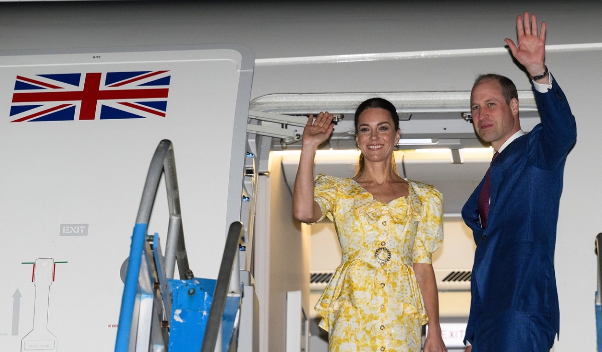 Kate Middleton într-o rochie galbenă alături de Prințul William îmbrăcat la costum în timp ce îi salută pe oamenii dn aeroportul din Bahamas de la bordul aeronavei cu care au sosit în luna martie a anului 2022