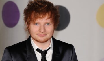 Ed Sheeran îmbrăcat la costum în timp ce participă la BRIT Awards în anul 2013