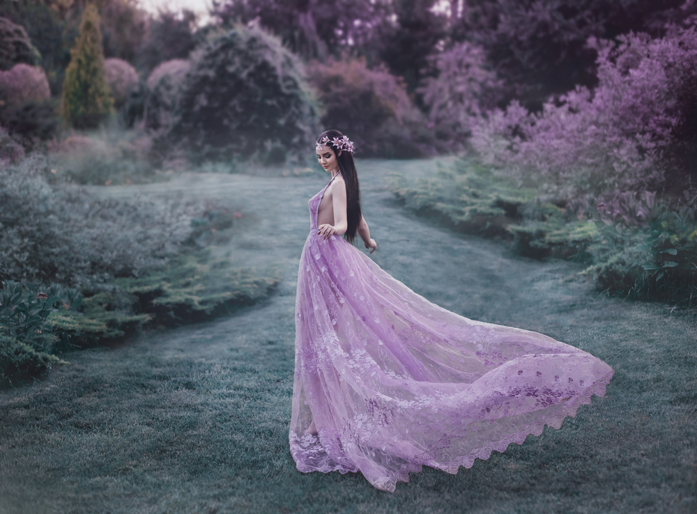 Fată frumoasă îmbrăcată într-o rochie mov merge prin pădure
