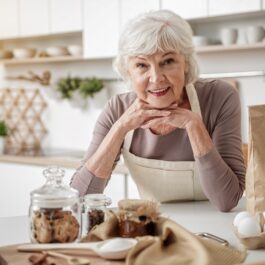 O femeie în vârstă care stă în fața unui blat de bucătărie pentru a ilustra acele alimente recomandate după vârsta de 70 de ani
