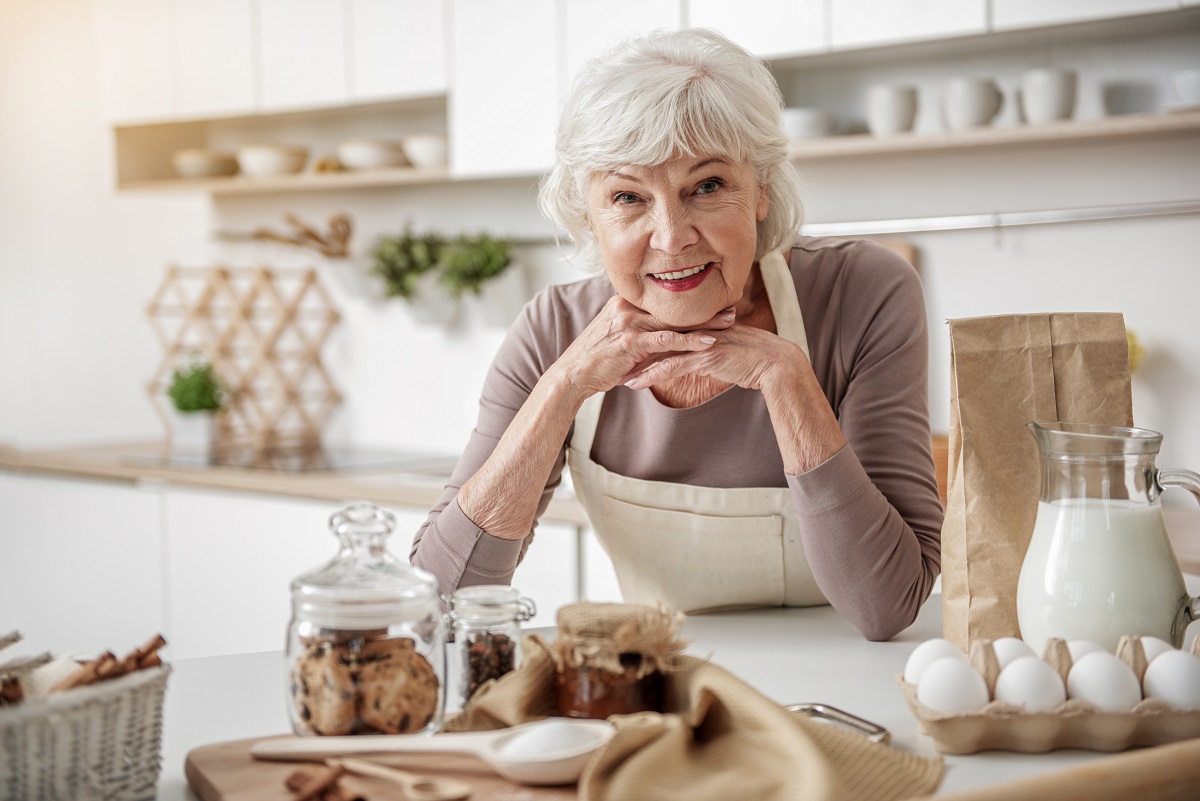 O femeie în vârstă care stă în fața unui blat de bucătărie pentru a ilustra acele alimente recomandate după vârsta de 70 de ani