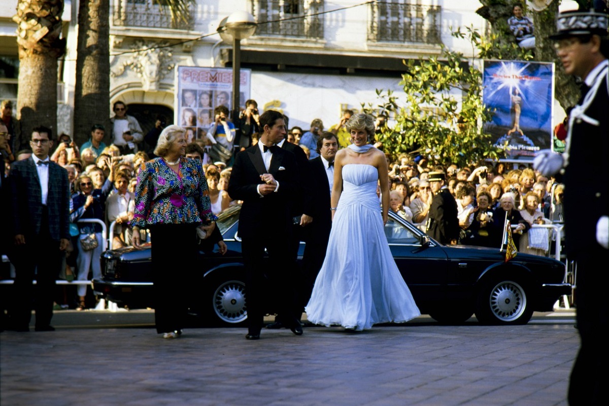 Prințul Charles la costum alături de Prințesa Diana, care poartă o rochie albastră, în timp ce sosesc la Festivalul de Film de la Cannes 1987