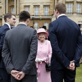 Regina Elisabeta în timp ce vorbește cu trei dintre participanții la petrecerile din grădinile Palatului Buckingham