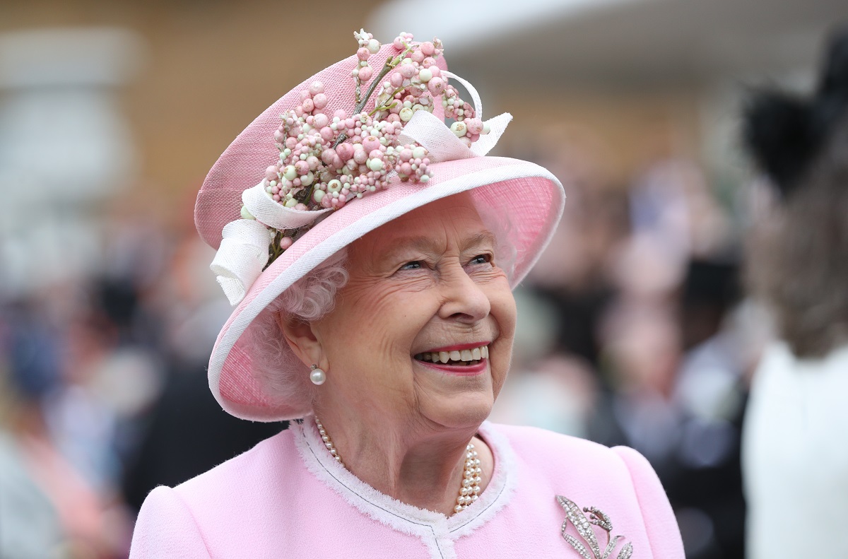 Regina Elisabeta într-un costum roz în timp ce participă la petrecerile din grădina Palatului Buckingham în anul 2018