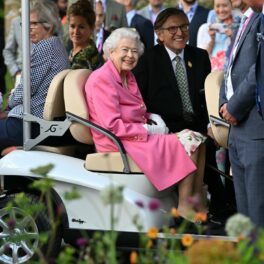 Regina Elisabeta, zâmbitoare, într-o mașină de golf, la un eveniment cu flori