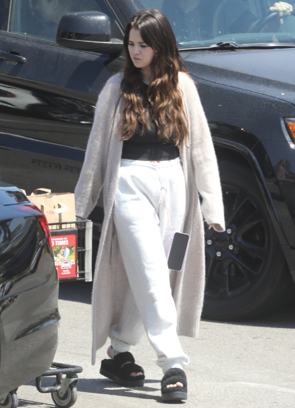 Selena Gomez într-o pereche de pantaloni albi și un tricou negru peste care a asortat un cardigan crem în timp ce s-a plimbat pe străzile din Malbu